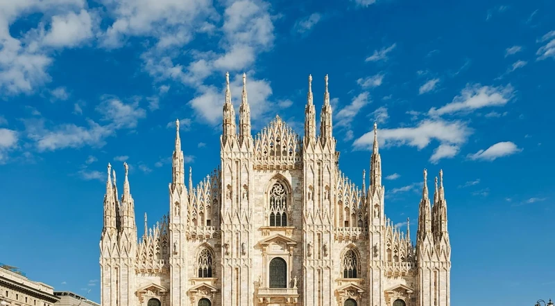 Front facade of the Duomo di Milano under a bright blue sky
