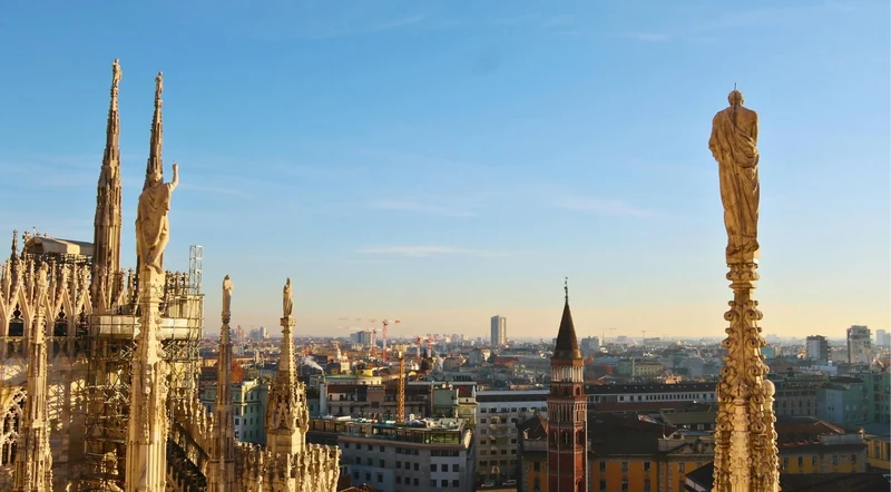 Golden light across Milan Duomo rooftop statues and spires above the city